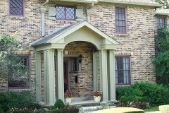 Brick home with a painted portico, columns and shutters in soft sage green