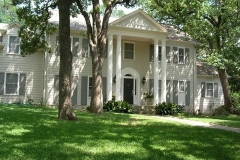 Two-story white colonial home with painted columns, pediment and shutters