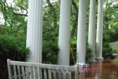 Porch swing and painted columns on a covered porch with a red stained concrete floor