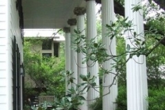 White painted porch columns along a covered front porch with a stained floor