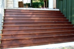 Wide stained wood steps leading to a covered porch