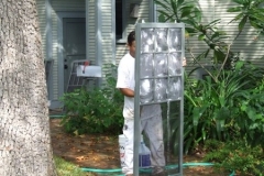 Removing a window unit for glass block installation during an exterior project. Additional services from our Austin painting contractors.