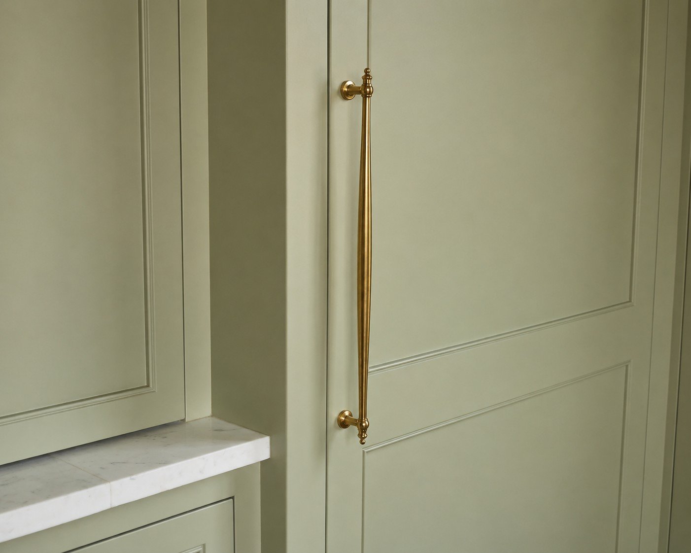 Sage green painted kitchen cabinet with brass hardware, professionally refinished by Austin cabinet painting contractor