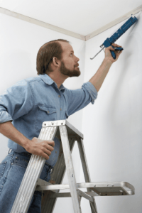 Painter caulking an interior wall corner before painting